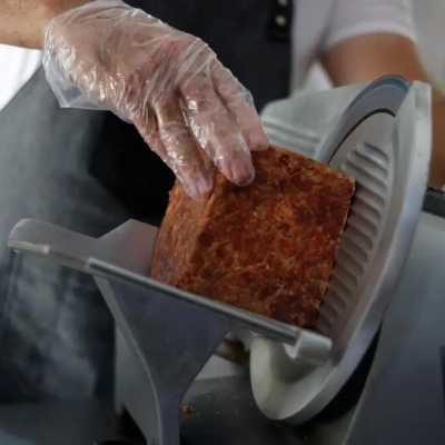 A man cutting meat on a slicer