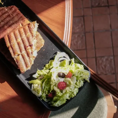 عکاسی پنینی مرغ و سالاد روی میز چوبی